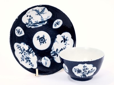 Lot 6 - Good Lowestoft tea bowl and saucer, the powder blue ground with lobed panels of flowers and a Chinaman, smaller panels of insects, florets and birds in flight, saucer 12.2cm diameter
