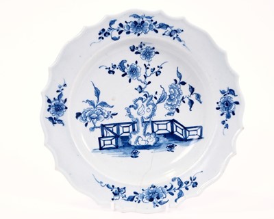 Lot 7 - Lowestoft plate, with thickened and shaped rim, painted in blue with flowers and rockwork within a fenced garden, sprigs in the border, 22.2cm diameter
