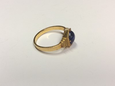 Lot 508 - Art Deco yellow metal oval blue cabochon sapphire ring in four claw setting with stepped cut shoulders. Possibly Indian gold. Ring size L½