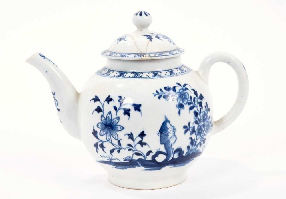 Lot 13 - Lowestoft teapot, of globular form with a curved spout and button finial, painted in blue with flowers and rockwork within a diaper border, 13cm high