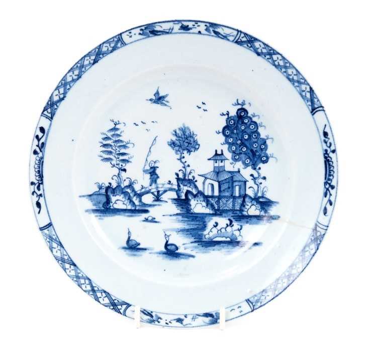 Lot 27 - Lowestoft plate, painted in blue with a chinaman crossing a bridge with a fishing rod, a bird in flight above, diaper and half-flowerhead border, 22.8cm diameter