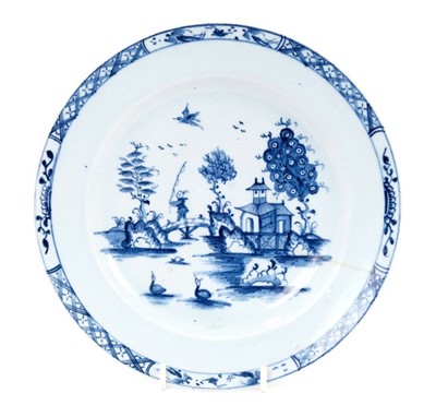 Lot 27 - Lowestoft plate, painted in blue with a chinaman crossing a bridge with a fishing rod, a bird in flight above, diaper and half-flowerhead border, 22.8cm diameter