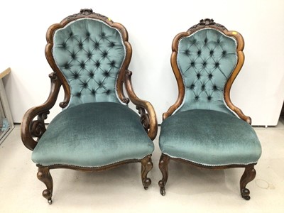 Lot 67 - Pair of mid Victorian rosewood 'his and hers'  easy chairs, with carved frames and blue showwood upholstery on castors