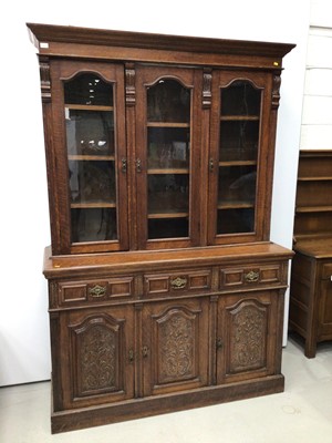 Lot 97 - Good quality Edwardian oak two height bookcase with adjustable shelves enclosed by three archers glazed doors, three drawers and cupboards below enclosed by carved panelled doors, 155cm wide x 226c...