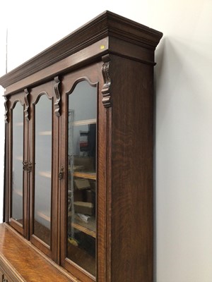 Lot 97 - Good quality Edwardian oak two height bookcase with adjustable shelves enclosed by three archers glazed doors, three drawers and cupboards below enclosed by carved panelled doors, 155cm wide x 226c...