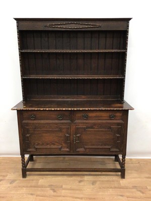 Lot 176 - 1920's oak two height dresser with shelves above, two drawers and two geometric panelled doors below on bobbin turned legs joined by stretchers, 136cm wide, 46.5cm deep, 191cm high