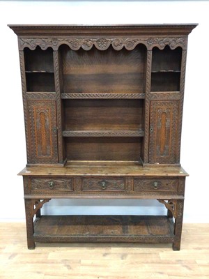 Lot 180 - Antique heavily carved oak two height dresser with open shelves and two carved cupboards above, three drawers and pot board below, 153cm wide, 39cm deep, 198cm high