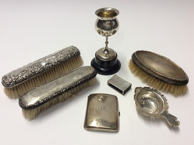 Lot 563 - Group silver to include three silver backed brushes, silver cigarette case, silver matchbox holder, silver tea strainer and small silver trophy on stand