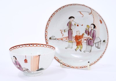 Lot 57 - Lowestoft tea bowl and saucer, painted in the Mandarin style with three figures, one smoking a pipe, within a red overlapping loop border, saucer 12.1cm diameter