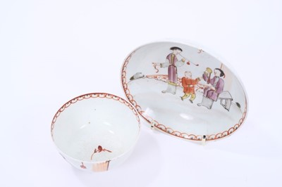 Lot 57 - Lowestoft tea bowl and saucer, painted in the Mandarin style with three figures, one smoking a pipe, within a red overlapping loop border, saucer 12.1cm diameter