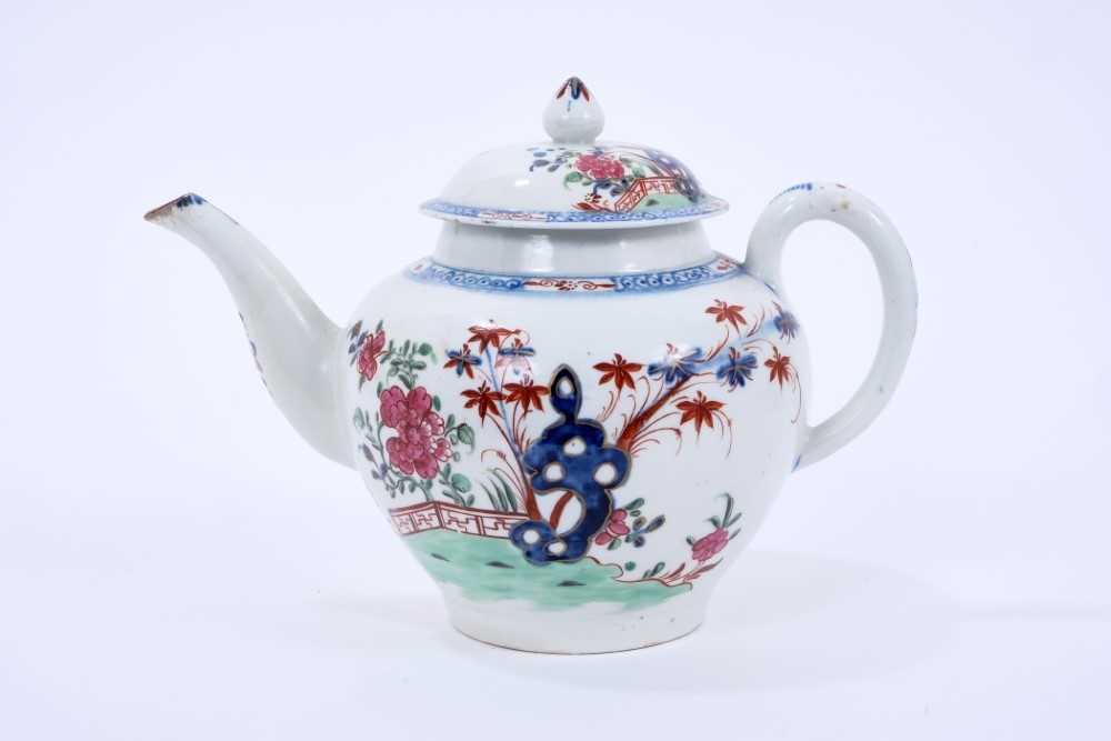 Lot 63 - Large Lowestoft teapot and cover, of globular form with a curved spout and mushroom finial, painted in colours with rockwork and plants within a fenced enclosure, the underglaze blue border with ir...