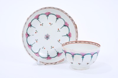 Lot 65 - Lowestoft tea bowl and saucer, enamelled with a wheel-like design in green and pink, within a red and black ermine border, 11.9cm diameter