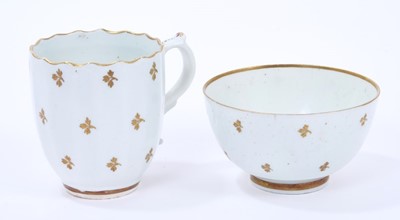 Lot 71 - Lowestoft coffee cup, of faceted form with scrolled handle and a shaped rim picked out in gold, gilded with regularly spaced sprigs, 6.7cm high, and a tea bowl of plain form, with similar decoratio...