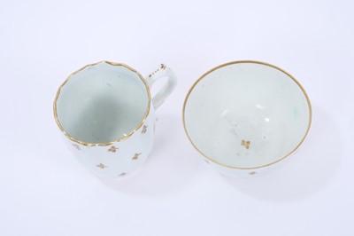 Lot 71 - Lowestoft coffee cup, of faceted form with scrolled handle and a shaped rim picked out in gold, gilded with regularly spaced sprigs, 6.7cm high, and a tea bowl of plain form, with similar decoratio...