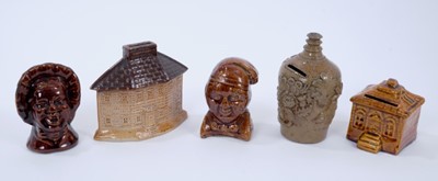 Lot 114 - Five 19th century pottery money boxes, including two treacle-glazed figural examples and a treacle-glazed house, a salt-glazed cottage form example and a salt-glazed bottle form example with sprigg...
