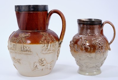 Lot 117 - Two 19th century salt glazed jugs, the larger with relief moulded tavern and hunting scenes, stamped 'DOULTON LAMBETH' to base, with sterling silver mounted rim, 23.5cm high, the smaller jug with r...
