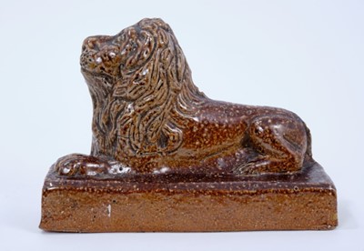 Lot 125 - 19th century salt glazed stoneware pottery door stop in the form of a lion, 18.5cm wide x 12.5cm high, a further salt glazed model of a lion, and a treacle glazed model of a lion (3)