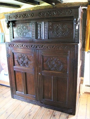 Lot 1500 - 17th century carved oak court cupboard, the upper section with scroll carved pendant canopy and two relief carved doors with fielded panel doors below, 141cm wide x 59cm deep x 178cm high