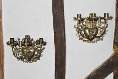 Lot 1523 - Pair of 19th century gothic brass three branch wall lights, each with flaming heart bracket insuring three candle arms, 22cm high