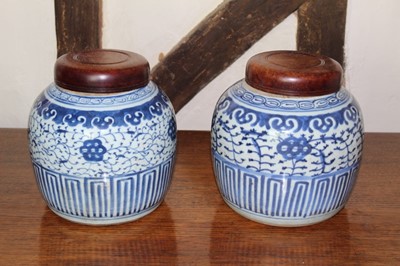 Lot 1532 - Pair of 18th century Chinese blue and white porcelain ginger jars, each with hardwood cover, decorated with lappet borders and scrolling foliage, 22cm high