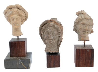 Lot 1735 - Three Greco-Roman terracotta sculptural fragments of female heads, each presented on plinth bases, the largest 13cm high