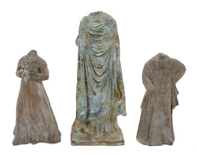 Lot 1736 - Tanagra terracotta figure of a headless woman, in draped costume, 17cm high, together with two similar smaller figures