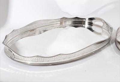 Lot 413 - Near pair of large Edwardian silver plated gallery trays of oval form with pierced gallery and gadrooned borders, raised on bun feet, each stamped 'silver on copper', each 61cm in length (2)