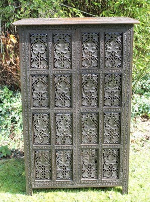 Lot 1760 - Late 19th/early 20th century Eastern carved and pierced hardwood collapsible cabinet, the rectangular arabesque relief carved top inlaid with brass panel, enclosed by a pair of doors, all over carv...