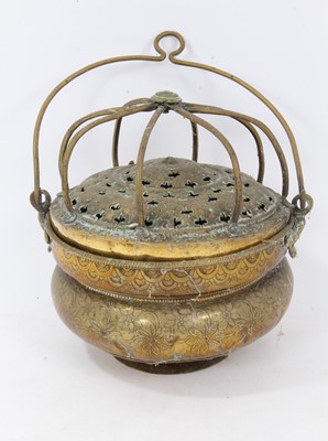 Lot 879 - 17th century brass censer, with pierced domed cover and surmounting cage, the squat vessel with foliate ornament and swing handle, 18cm diameter 
Provenance: Estate of the Late Jane Sumner