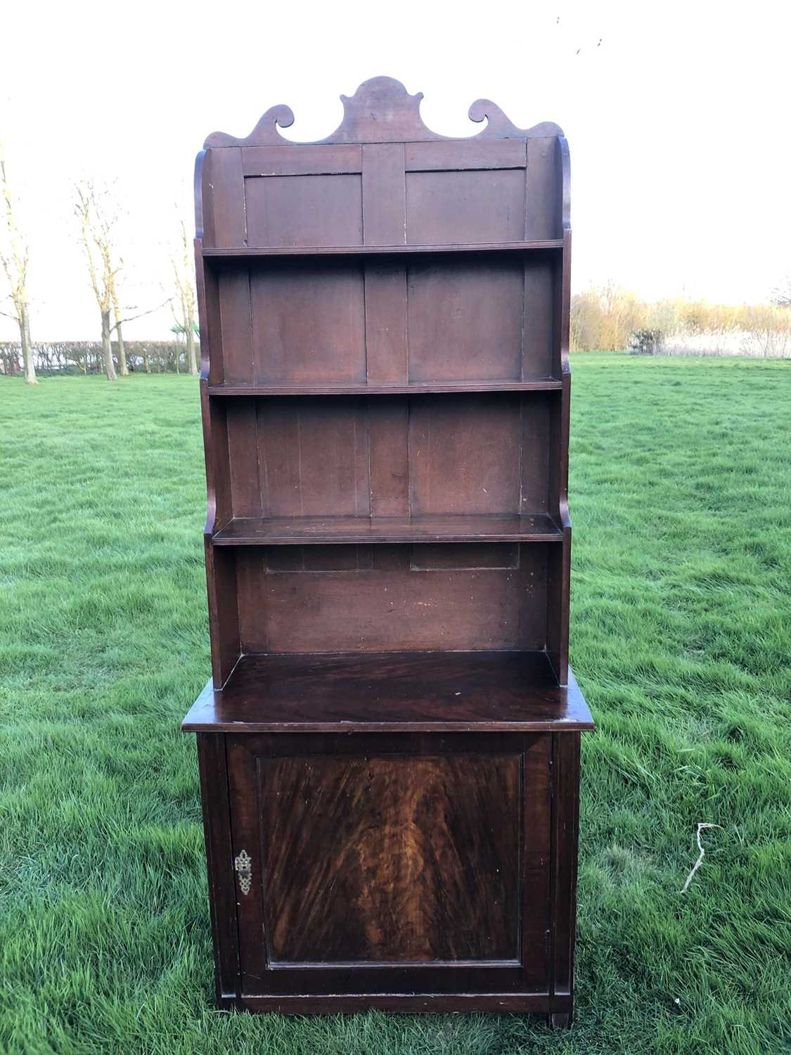 Lot 977 - 19th century mahogany and grained waterfall bookcase with scrolling top rail and graduated open shelves, enclosed panel cupboard below, on tapering legs, 78cm wide x 38cm deep x 190cm high