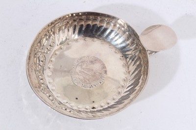 Lot 304 - George V silver wine taster of circular form with chased decoration, the base set with an Elizabethan silver hammered coin, with circular handle and oval thumb piece, (London 1912), makers mark rub...