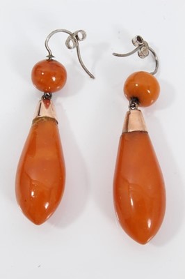 Lot 479 - Victorian amber brooch and earrings, the torpedo shape pendant earrings suspended from a gold mount with coral bead, 60mm, the oval brooch 42mm, all in original fitted box.