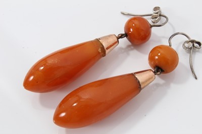 Lot 479 - Victorian amber brooch and earrings, the torpedo shape pendant earrings suspended from a gold mount with coral bead, 60mm, the oval brooch 42mm, all in original fitted box.