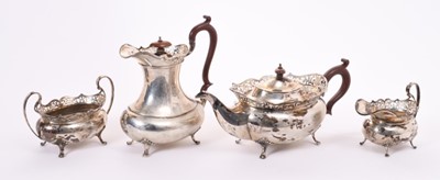 Lot 344 - George V four piece silver teaset comprising, teapot of compressed baluster form with pierced flared border, scroll handle and hinged domed cover with oval finial, on four paw feet, matching coffee...