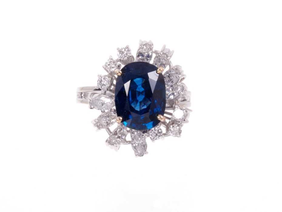 Lot 488 - Sapphire and diamond cluster cocktail ring with an oval mixed blue sapphire measuring approximately 11.75mm x 8.75mm x 5.75mm, surrounded by an asymmetric border of brilliant cut and marquise cut d...