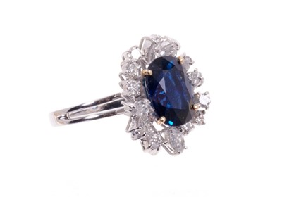 Lot 488 - Sapphire and diamond cluster cocktail ring with an oval mixed blue sapphire measuring approximately 11.75mm x 8.75mm x 5.75mm, surrounded by an asymmetric border of brilliant cut and marquise cut d...