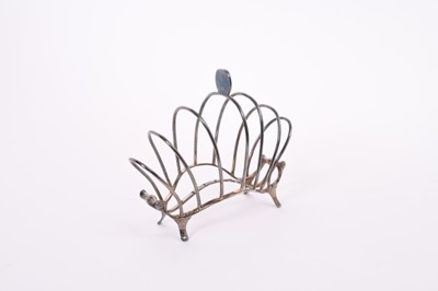 Lot 363 - Edwardian wire frame toast rack of arched form with scroll ends, raised on four bracket feet, (London 1905), maker William Comyns & Sons, all at approximately 5oz, 14cm in length