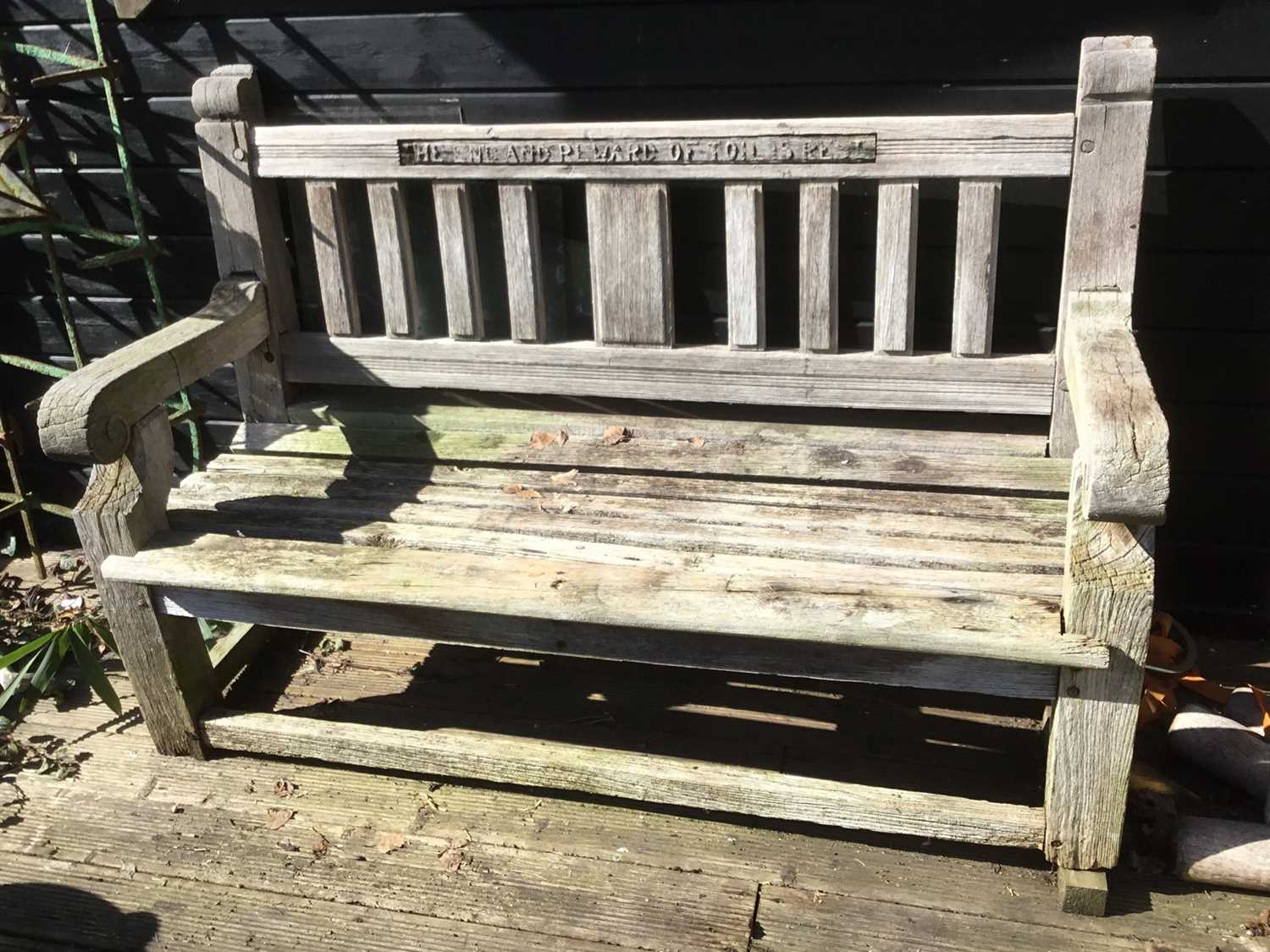 Lot 1851 - Teak garden bench with carved motto to the top rail ‘The End And Reward Of Toll Is Rest’, 130cm wide