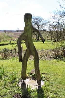 Lot 1854 - Carved wood sculpture in the form of a man utilising the natural form of the wood, raised on circular state stand, 172cm high