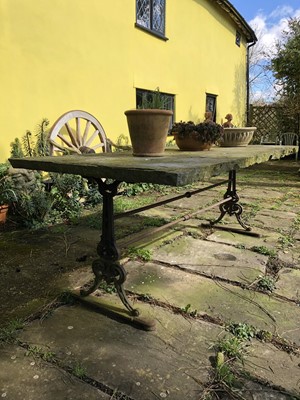 Lot 1865 - Massive garden table with rectangular York stone top, supported on a cast iron base with shaped standard ends, 205cm long x 100cm wide