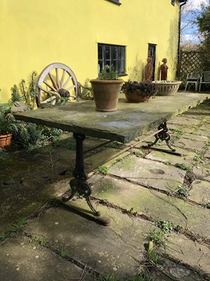 Lot 1865 - Massive garden table with rectangular York stone top, supported on a cast iron base with shaped standard ends, 205cm long x 100cm wide