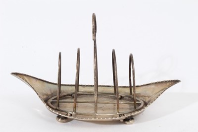 Lot 423 - Edwardian silver wire frame four division toast rack on tray of navette form with egg and dart borders, raised on bun feet, (Chester 1908), maker George Nathan & Ridley Hayes, all at 7oz, 21cm in l...