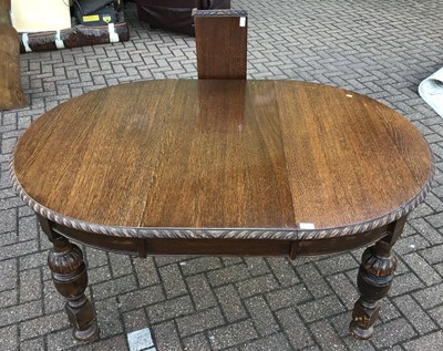 Lot 227 - 1920's oak oval extending dining table with one extra leaf on carved cup and cover legs, opening to 173cm x 110cm