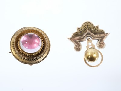 Lot 555 - Two Victorian Etruscan Revival gold brooches, one with a large pink foil backed cabochon in circular gold target shape setting with applied filigree and glazed locket compartment to the reverse, 35...