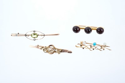 Lot 558 - Four Edwardian gold and gem-set bar brooches to include cabochon garnet bar brooch in 15ct gold setting, an Edwardian rose gold turquoise and seed pearl bar brooch, a peridot brooch and a seed pear...