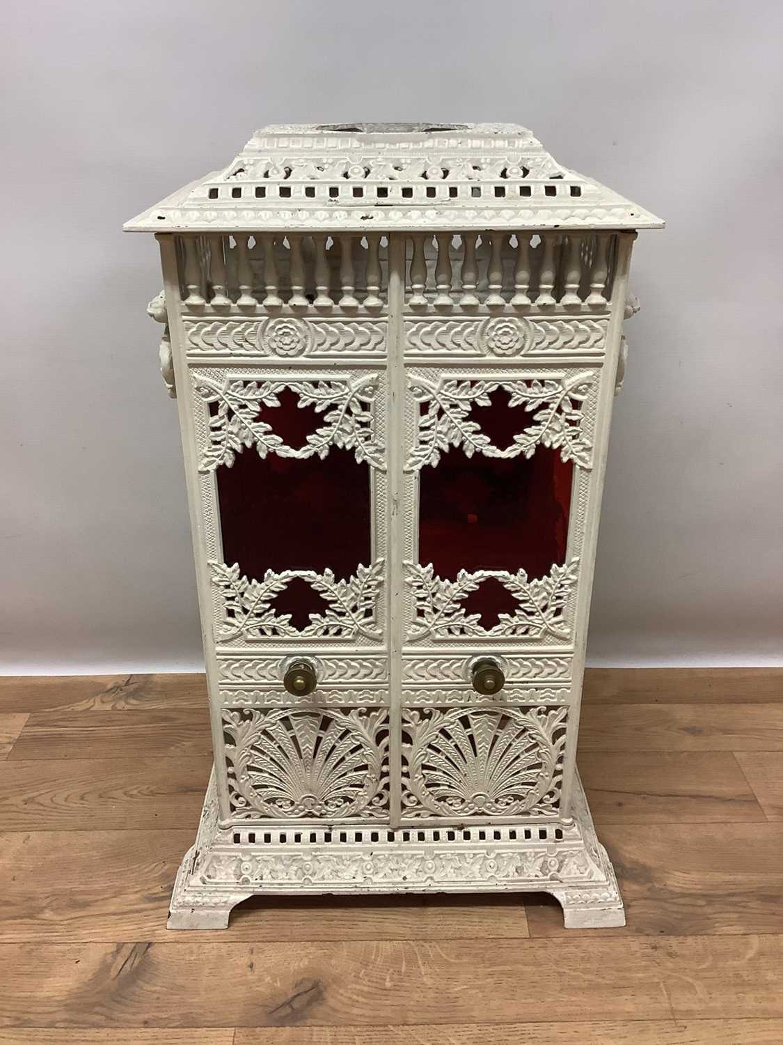 Lot 1355 - Victorian white painted cast iron conservatory heater, titled Veritas Stove, in the aesthetic taste, of square pillar form with elaborate geometric and foliate ornament and coloured glass inset pan...