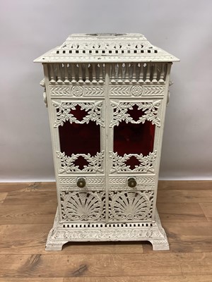 Lot 1355 - Victorian white painted cast iron conservatory heater, titled Veritas Stove, in the aesthetic taste, of square pillar form with elaborate geometric and foliate ornament and coloured glass inset pan...