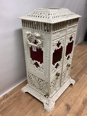 Lot 1355 - Victorian white painted cast iron conservatory heater, titled Veritas Stove, in the aesthetic taste, of square pillar form with elaborate geometric and foliate ornament and coloured glass inset pan...