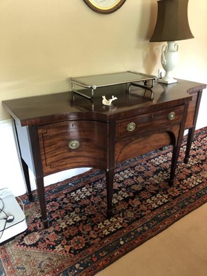 Lot 1371 - George III mahogany sideboard, the central long drawer and frieze drawer below flanked by concave deep drawers, each line-inlaid with brass oval ring handles, on fluted and reeded square taper legs...