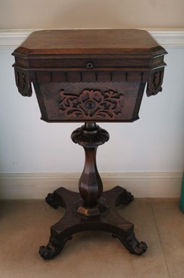 Lot 1444 - Early Victorian rosewood teapoy with canted rectangular top over a lappet carved frieze and fret carved panel, on faceted baluster column and quatrefoil base, raised on scroll feet and castors, 46c...